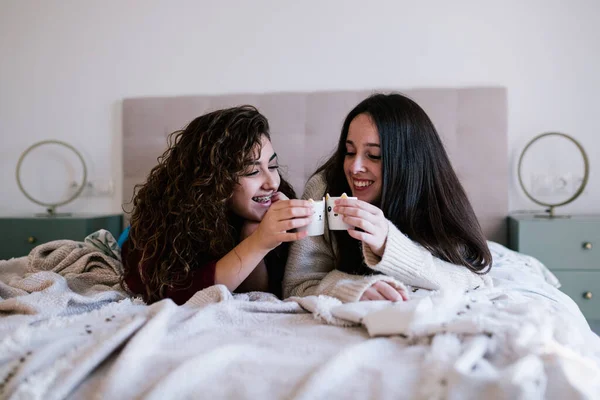 İki beyaz kadın bir bardak kahveyle kadeh kaldırıyor.