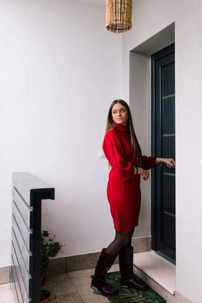 Ön kapısını açan kırmızı elbiseli genç bir kadının profil görüntüsü. Zor bir günün ardından öğrenci. İş kadını işten geliyor.