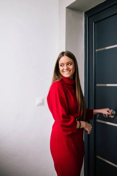 Ön kapısını açan kırmızı elbiseli genç bir kadının profil görüntüsü. Zor bir günün ardından öğrenci. İş kadını işten geliyor.