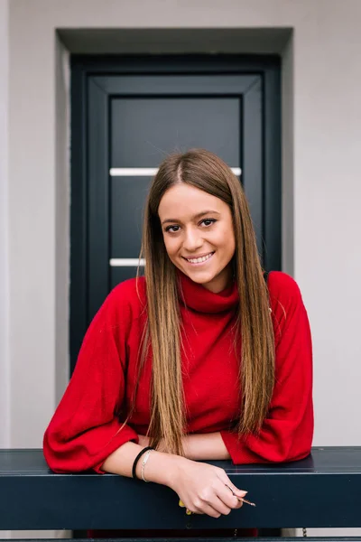 Evin kapısında kameraya gülümseyen sarı saçlı bir kadının yakın çekimi. Mutlu kadın. İş kadını.