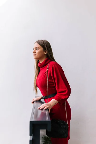 Uzun sarı saçlı genç kız dışarıda yağmur yağıyor mu diye bakmak için elini uzatarak evin kapısına doğru eğildi.