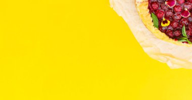 Sarı arka planda yenilebilir çiçeklerle süslenmiş vişneli turta. Kavram pişirme, yemek kitabı tarifleri, pastane afişi, kafe reklamı. Bahar, yaz ve tatil satışları. Merhaba yaz.