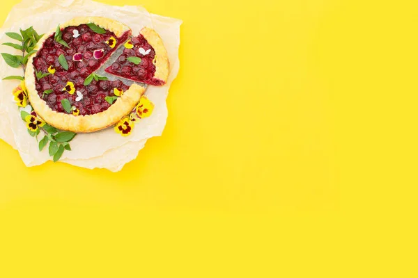 Spring cherry pie, decorated with edible flowers on a yellow background. Concept baking, cookbook recipes, bakery banner, cafe advertisement. Vacation sales spring, summer and holiday. Hello summer