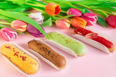 Eclairs and vibrant tulips and muscari flowers. Still life Hello summer mood. Concept baking, cookbook recipes, bakery banner, cafe advertisement. Vacation sales summer and holiday.