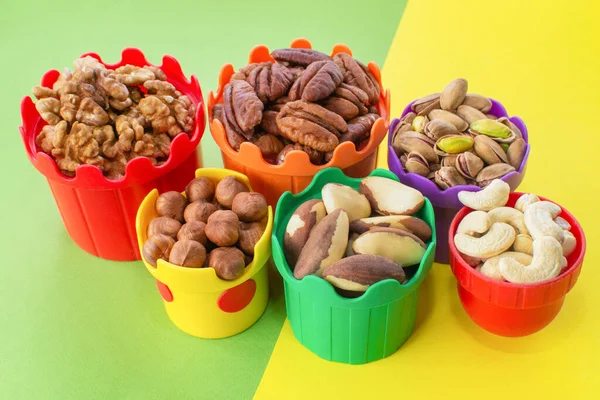 Renkli bardaklarda çocuklar için fındık. Ceviz, fıstık, fındık, fındık, fındık, fındık, fındık. Faydalı bir atıştırma. Sağlıklı yiyecekler, yararlı mikroelementler ve vitaminler, sağlıklı beslenme. Seçici Odaklanma