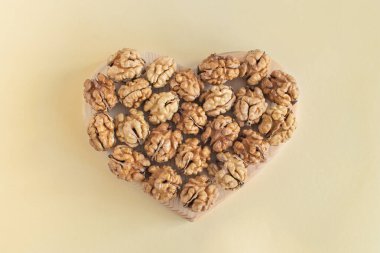 Organik cevizler kalp şeklinde. Kalp için sağlıklı yiyecekler, kullanışlı mikro elementler ve vitaminler. Vejetaryenler ve daha fazlası için faydalı bir atıştırmalık. Sağlıklı Konsept.