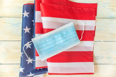 Arka planda tıbbi maske ve ahşap arka planda Amerikan bayrağı. 4 Temmuz Bağımsızlık Günü ABD Emniyeti.