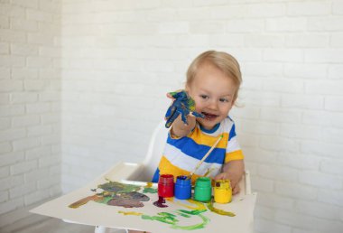 Boyalı çocuk çizimi, kahkahalar kirli elleri boyayla gösteriyor. Çocukların yaratıcı oyunları. Yaratıcılık için eğitici oyuncakları olan bir çocuk. Çocuk evde oynuyor. Parlak boya lekeli bir çocuğun elleri..