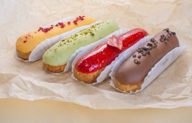 Eclairs on a craft paper background. Still life hello dessert mood. Traditional French dessert with colorful icing. Concept baking, cookbook recipes, bakery banner, cafe advertisement