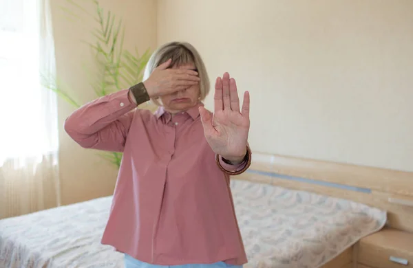 Mujer mayor sigraliza gesto de la mano Detener en su fondo dormitorio. Concepto libertad, salud psicológica, salud mental saludable — Foto de Stock