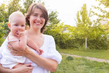 Bahçede annesinin ellerinde tatlı bir bebek. Anne bebeğe sevgiyle sarılıyor. Annelik kavramı