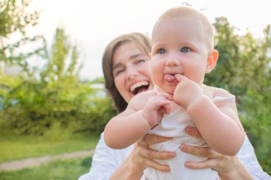 Gülümseyen anne ve küçük sarışın kız bahçede eğleniyorlar. Mutlu bir ailenin aktif boş vakitleri.