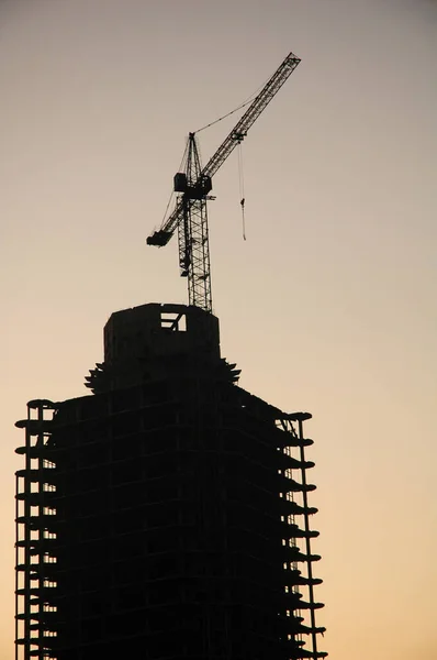 Silhouette of a building under construction with a construction crane