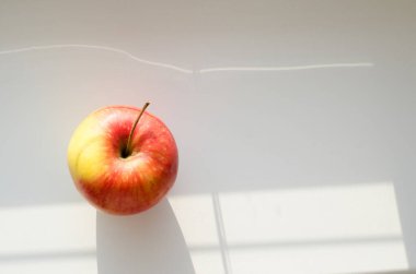 Açık arkaplanda kırmızı ve sarı elma ve pencereden güzel bir ışık.