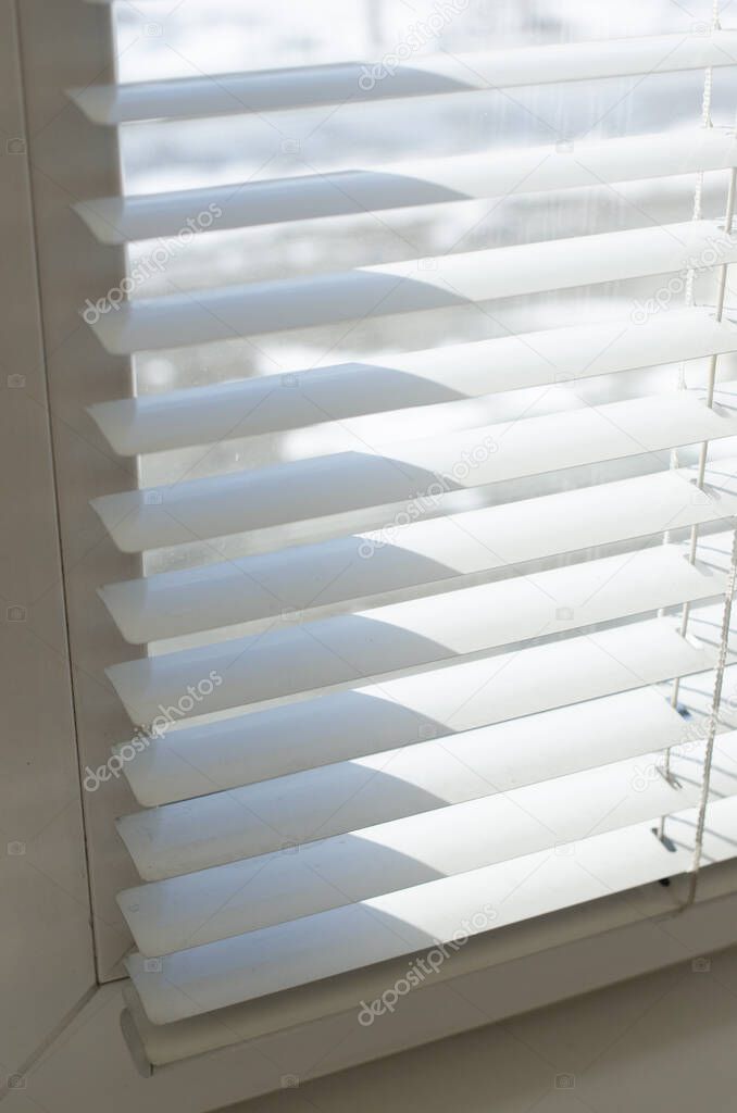 White blinds close up against the light from the window