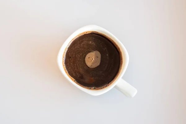 Coffee foam swirls in white cup with black coffee