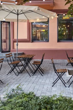 Terastaki masa ve sandalyeler bahçeli boş sokak kafesi