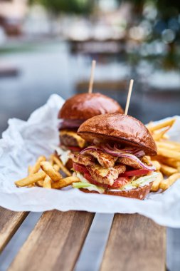 Burgerler ve patates kızartmaları yerel bir kafedeki ahşap masada.