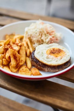 Şnitzel, yumurta patatesli ve lahanalı sokak terasındaki ahşap masada yaz mevsimi.