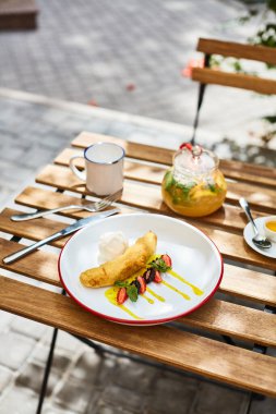 Yerel bir kafe deniz dikenli çayın terasında kahvaltı ve meyve ve karamel ile kızarmış muz tatlısı.