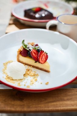 Çilekli cheesecake ve dondurma masada diğer tatlılarla birlikte.