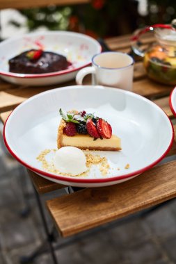 Çilekli cheesecake ve dondurma masada diğer tatlılarla birlikte.