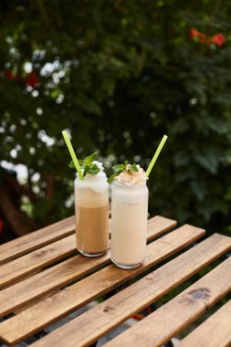 Ahşap bir masada, restoranın terasında iki bardak milkshake.