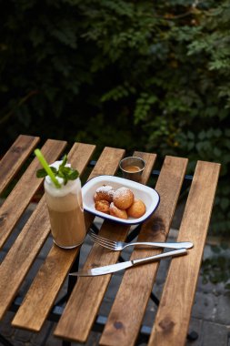 Bahçe çöreklerinde kahvaltı ve ahşap masada milkshake.