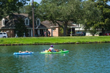 NEW ORLEANS, LA, ABD - 27 Eylül 2020: Erkek kano sürüyor ve arka planda erkek ve kadın boksu ile Bayou St. John 'da çocuk çekiliyor