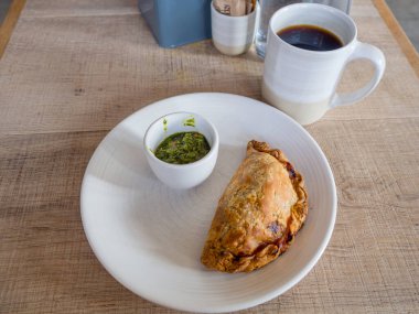 Chimichurri soslu Empanada ve bir fincan kahve.