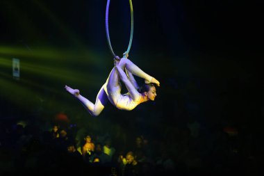 Atletik kadın model, hava çemberi performansı, güçlü esnek vücut, sarı ışık, esneme egzersizleri..