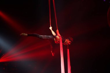 Brezilyalı güçlü seksi adam kırmızı ışıklarda hava ipekleriyle performans sergiliyor. Spor salonu ve yaşam tarzı konsepti.