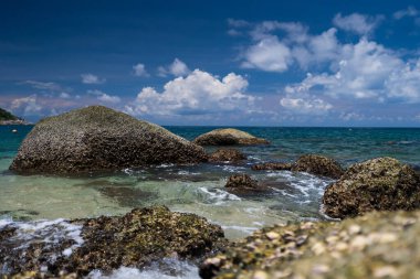 Doğal tema üzerine dekorasyon için büyük taş resif plajı arka planı. Granit taşlı açık mavi deniz suyu.