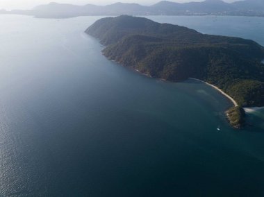 Tropikal ada, gün batımında gökyüzünden, dağdan, küçük serbest plajdan, Phuket şehrinin ve dağların arkasından. Seyahat konsepti