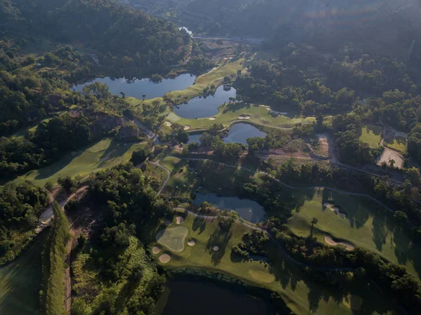 Şafak vakti evlerle ve dağlarla çevrili bir golf sahasında bulunan güzel göl. İnsansız hava aracının fotoğrafı. Gölde, gökyüzünün yansıması. Seyahat ve golf reklamı için harika bir geçmiş..
