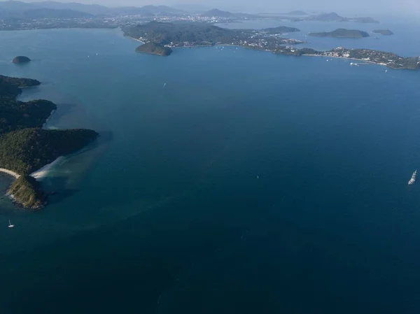 Tropikal ada, gün batımında gökyüzünden, dağdan, küçük serbest plajdan, Phuket şehrinin ve dağların arkasından. Seyahat konsepti