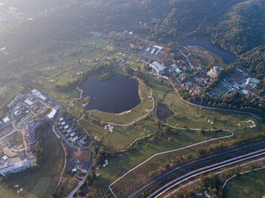 Şafak vakti evlerle ve dağlarla çevrili bir golf sahasında bulunan güzel göl. İnsansız hava aracının fotoğrafı. Gölde, gökyüzünün yansıması. Seyahat ve golf reklamı için harika bir geçmiş..