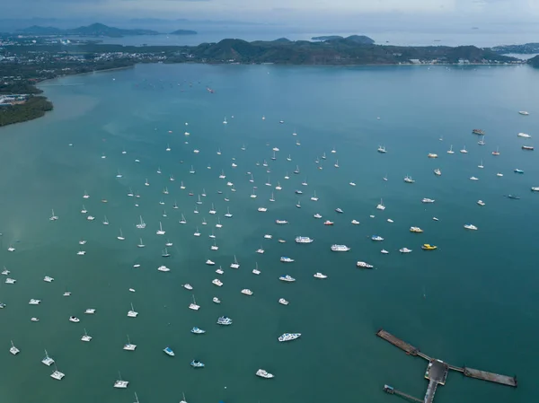 Körfez manzaralı yat parkı, koy resimli dağlarla çevrili, gün batımında bulutlu hava. Park halindeki teknelerle çevrili bir rıhtım manzarası, Chalong Körfezi Phuket Tayland