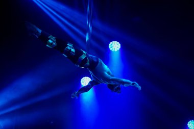 Amerikalı güçlü seksi adam hava kayışlarında performans sergiliyor mavi ve sarı ışıklarda, hava kayışlarında. Spor salonu ve yaşam tarzı konsepti.