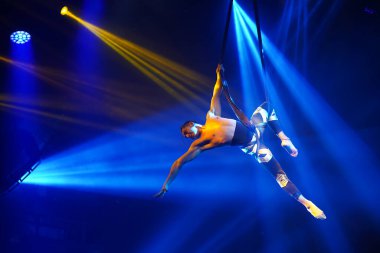 Amerikalı güçlü seksi adam mavi ışıkta hava kayışında performans sergiliyor. Spor salonu ve yaşam tarzı konsepti. Siyah arkaplan.