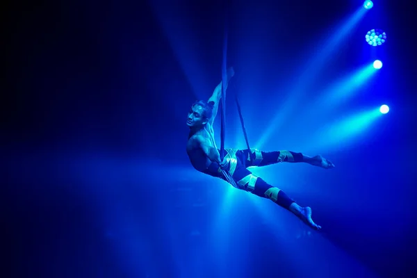 Amerikalı güçlü seksi adam hava kayışlarında performans sergiliyor mavi ve sarı ışıklarda, hava kayışlarında. Spor salonu ve yaşam tarzı konsepti.