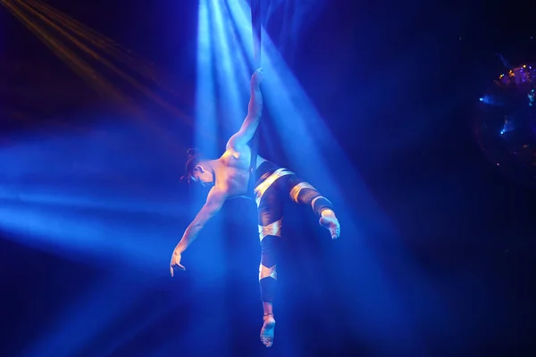 Amerikalı güçlü seksi adam mavi ışıkta hava kayışında performans sergiliyor. Spor salonu ve yaşam tarzı konsepti. Siyah arkaplan.