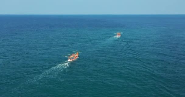 Łodzie rybackie z lotu ptaka. Małe statki pływają po powierzchni morza, pozostawiając ścieżkę piankowej wody morskiej — Wideo stockowe