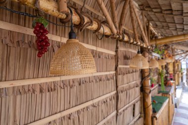 Geleneksel kulübenin samanlı çatısına karşı bambu çiftçi şapkasıyla süslenmiş 2 klasik asma lambası ön planına odaklanın. Yüksek kalite fotoğraf