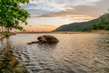 Güzel Sunset turuncu gökyüzü ve gölün ortasında kaya, arka planda yeşil tepeler, Nai harn gölü, Phuket.