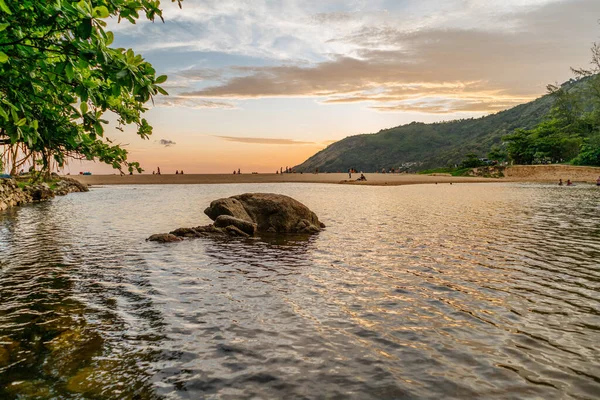 Güzel Sunset turuncu gökyüzü ve gölün ortasında kaya, arka planda yeşil tepeler, Nai harn gölü, Phuket.