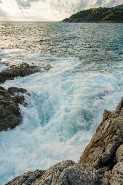 Mercan taşları ve deniz dalgaları gün batımında kayalara çarpıyor.
