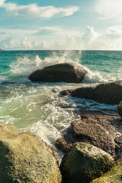 Korallensteine und Meereswellen treffen bei Sonnenuntergang auf die Felsen. Vertikales Foto — Stockfoto