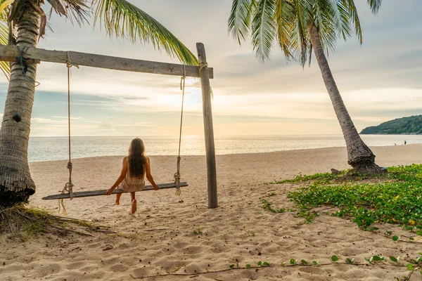 Das Mädchen schaukelt auf der Schaukel und blickt auf den Sonnenuntergang am tropischen Strand. Freiheit, Freizeit, Urlaub, Reisekonzept — Stockfoto