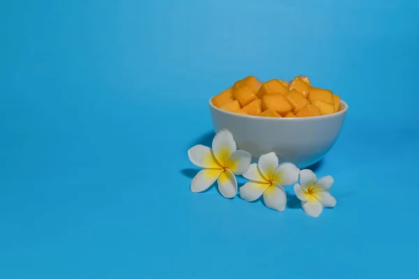 Tropikal meyve, beyaz çiçekli beyaz kasede sarı mango küp dilimleri. Boşluğu kopyala